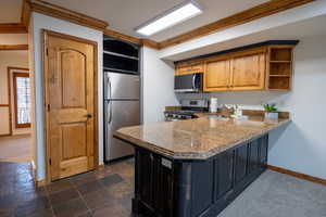 Kitchen featuring appliances with stainless steel finishes, light stone counters, crown molding, sink, and dark colored carpet