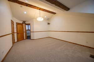 Carpeted empty room with lofted ceiling with beams