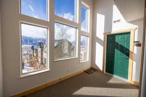 Foyer with a mountain view, a high ceiling, and carpet floors