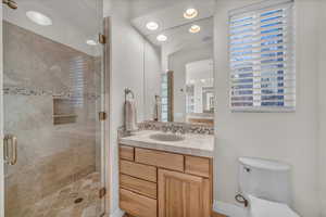 Bathroom with tasteful backsplash, plenty of natural light, an enclosed shower, and toilet