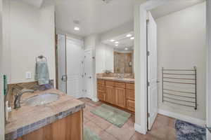 Bathroom featuring tasteful backsplash, tile patterned flooring, vanity, and an enclosed shower