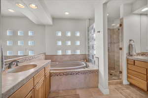 Bathroom with tile patterned floors, vanity, and shower with separate bathtub