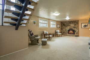 Sitting room featuring carpet flooring, a textured ceiling, and a stone fireplace