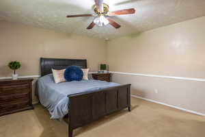 Carpeted bedroom with a textured ceiling and ceiling fan