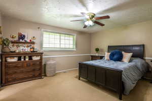 Carpeted bedroom with ceiling fan and a textured ceiling