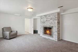 Unfurnished room with carpet floors, a textured ceiling, and a tiled fireplace