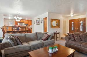 Living room featuring light carpet, a chandelier, and a textured ceiling