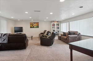 Living room with light colored carpet and a textured ceiling