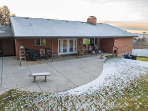 Snow covered back of property featuring a patio area and french doors