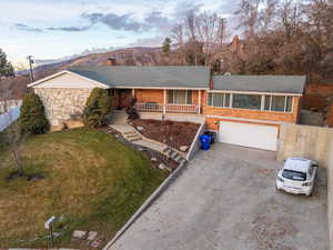 Ranch-style home featuring covered porch, a mountain view, a garage, and a front lawn