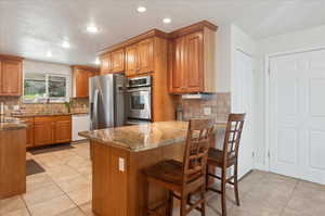 Kitchen with kitchen peninsula, stainless steel fridge, white dishwasher, sink, and stone counters