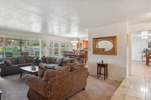 Living room with french doors, light tile patterned flooring, a chandelier, and a textured ceiling