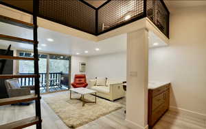 Living room with floor to ceiling windows, a high ceiling, light hardwood / wood-style flooring, and a wall mounted air conditioner