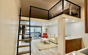 Living room with a high ceiling, a wall of windows, and light hardwood / wood-style flooring