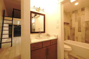 Full bathroom with wood-type flooring, vanity, bathing tub / shower combination, and toilet