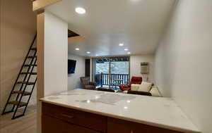 Kitchen with a wall unit AC, expansive windows, kitchen peninsula, and light wood-type flooring