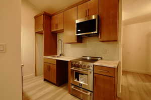 Kitchen featuring light wood-type flooring, backsplash, stainless steel appliances, and sink