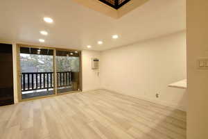 Unfurnished room featuring light wood-type flooring and a wall unit AC