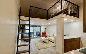 Living room with a wall of windows, a towering ceiling, and light hardwood / wood-style floors