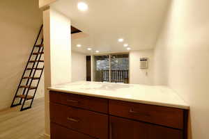 Kitchen featuring light stone countertops, light hardwood / wood-style floors, kitchen peninsula, and a wall mounted AC