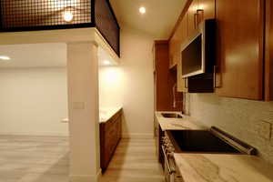 Kitchen with decorative backsplash, stainless steel stove, light hardwood / wood-style flooring, and sink