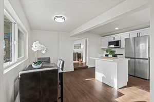 Dining room and kitchen featuring new cabinetry, stainless steel appliances, and hardwood / wood-style flooring