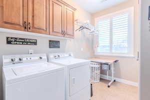 Clothes washing area featuring washing machine and dryer and cabinets