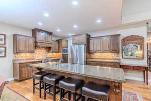 Kitchen with a kitchen breakfast bar, stainless steel appliances, a kitchen island with sink, sink, and light hardwood / wood-style floors