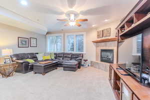 Carpeted living room featuring ceiling fan and a fireplace