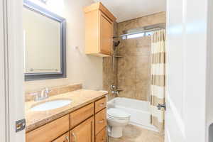 Full bathroom featuring toilet, vanity, shower / tub combo with curtain, and tile patterned flooring