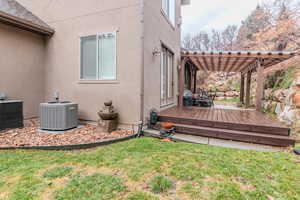 View of side of home featuring a yard, a pergola, central AC unit, and a wooden deck