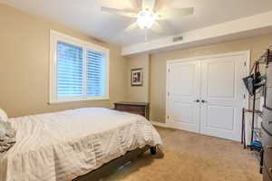 Bedroom featuring a closet, ceiling fan, and light colored carpet