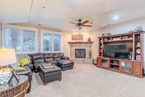 Carpeted living room with ceiling fan and a tile fireplace