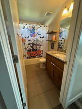 Full bathroom featuring shower / bath combination with curtain, vanity, toilet, and tile patterned floors