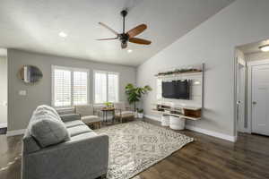 Living room featuring ceiling fan, dark hardwood / wood-style floors, a textured ceiling, and vaulted ceiling