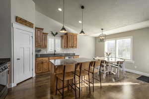 Kitchen featuring sink, vaulted ceiling, decorative backsplash, a kitchen island, and appliances with stainless steel finishes