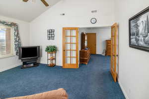 Living area featuring dark colored carpet, french doors, ceiling fan, and lofted ceiling