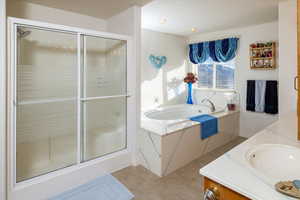 Bathroom featuring shower with separate bathtub and vanity