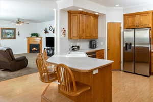 Kitchen featuring sink, ceiling fan, light wood-type flooring, kitchen peninsula, and stainless steel appliances