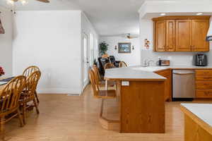 Kitchen featuring dishwasher, sink, ornamental molding, light hardwood / wood-style floors, and kitchen peninsula