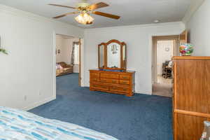 Carpeted Master Bedroom suite featuring ceiling fan, crown molding, and double doors to sitting room