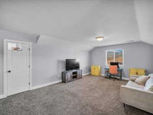 Carpeted living room featuring lofted ceiling