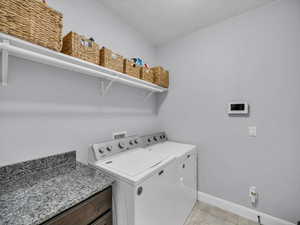 Washroom featuring washing machine and dryer and light tile patterned floors