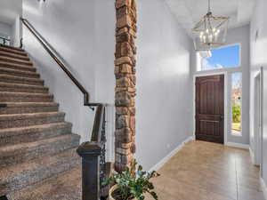 Tiled foyer with a towering ceiling and a chandelier