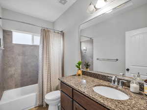 Full bathroom with shower / tub combo with curtain, vanity, and toilet