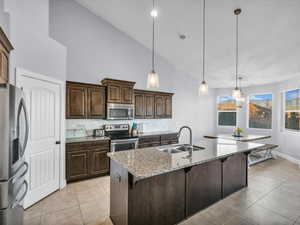 Kitchen with appliances with stainless steel finishes, a kitchen breakfast bar, sink, a center island with sink, and hanging light fixtures