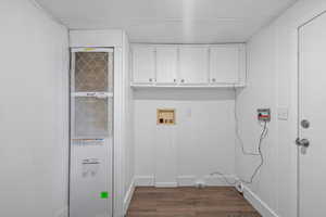 Clothes washing area with cabinets, dark wood-type flooring, and hookup for a washing machine