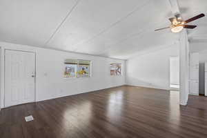 Unfurnished living room featuring dark hardwood / wood-style floors, vaulted ceiling, and ceiling fan