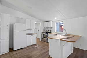 Kitchen with sink, white fridge, wood-type flooring, electric stove, and white cabinets