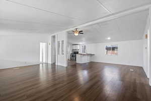 Unfurnished living room with vaulted ceiling with beams, ceiling fan, sink, and dark wood-type flooring